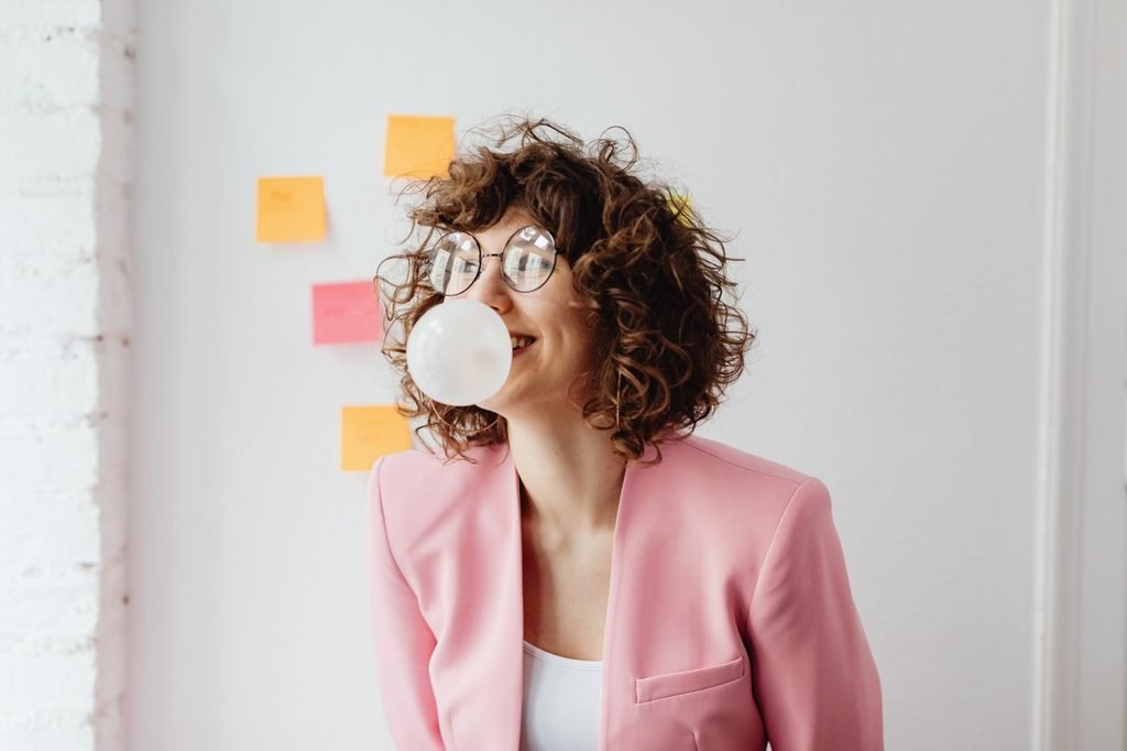 How to remove gum: woman blowing a bubble with chewing gum